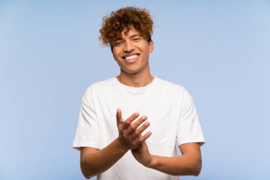 Beyaz gömlekli genç Afro-Amerikan adam alkışlıyor.