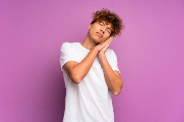 Genç Afro-Amerikan erkeği, mor duvarın üstünde, uyku jesti yapıyor.