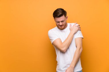 Kahverengi duvarın üzerinde redhead adam bir çaba yapmış için omuz ağrısı muzdarip