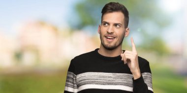Açık havada bir parmak kaldırırken çözümü fark etmek isteyen yakışıklı adam