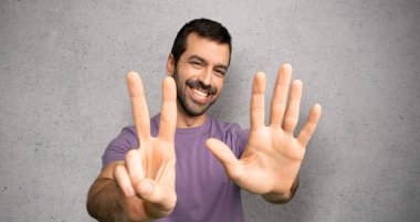 Yakışıklı adam altı parmaklar ile dokulu duvar üzerinde sayma