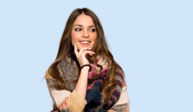 Genç hippi kadın yan ile izole mavi arka plan üzerinde çene üzerinde el arıyor