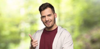 Sweatshirt ön işaret ve bir parkta gülümseyen adam