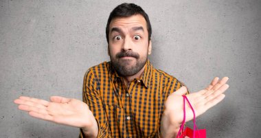 Dokulu duvar üzerinde eller ve omuzlar yetiştirirken şüpheleri olan alışveriş çantaları ile adam