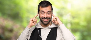 Spor adam bir parkta kulaklıklar ile müzik dinliyor