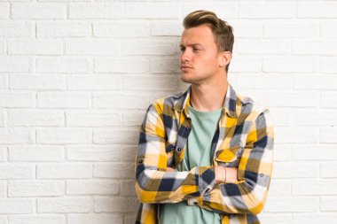 Beyaz tuğla duvar ayakta ve görünümlü yan üzerinde sarışın yakışıklı adam