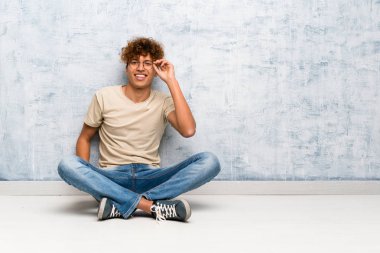 Genç afro-amerikan adam gözlükle yerde oturan ve şaşırttı