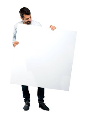 Boş bir afişini izole beyaz arka plan üzerinde tutarak sakallı yakışıklı adam tam uzunlukta atış