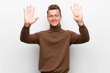 Sarışın adam dokuz parmaklı sayma izole beyaz duvar üzerinde