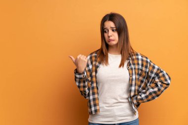 Kahverengi duvar üzerinde genç kadın mutsuz ve yan işaret