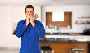 Evde ağız kapsayan çok gülümseyen ressam adam