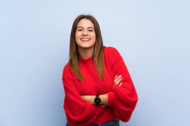 İzole mavi duvar üzerinde genç kadın silah tutmak frontal pozisyonda geçti