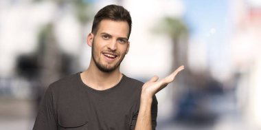 Siyah gömlek ile adam açık havada bir reklam eklemek için palmiye üzerinde boşaltmak hayali tutan