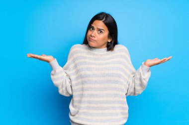 Süveteri olan genç Kolombiyalı kız ellerini ve omuzlarını kaldırırken şüphe duyuyor.