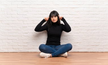 Kadın yerde oturuyor ve düşünüyor.