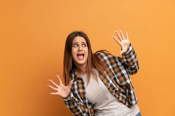 Young woman over brown wall nervous and scared