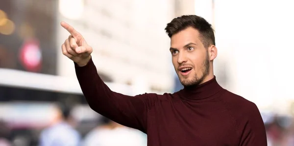 Man with turtleneck sweater pointing away in the city