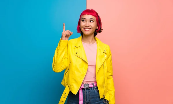 Young woman with yellow jacket intending to realizes the solution while lifting a finger up