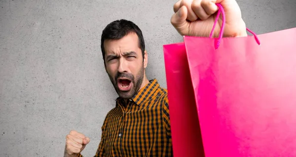Hombre Con Bolsas Compras Celebrando Una Victoria Sobre Pared Texturizada —  Fotos de Stock