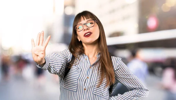 Gözlük mutlu ve açık havada parmaklarla dört sayma kadın