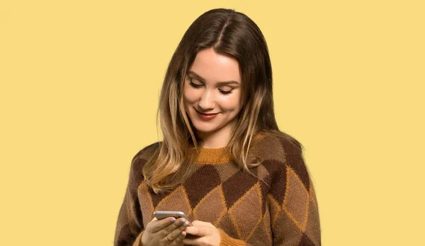 Teenagerka Hnědým Svetrem Který Posílá Vzkaz Mobilním Přes Izolované Žluté — Stock fotografie