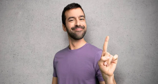 Hombre Guapo Mostrando Levantando Dedo Señal Mejor Sobre Pared Texturizada —  Fotos de Stock