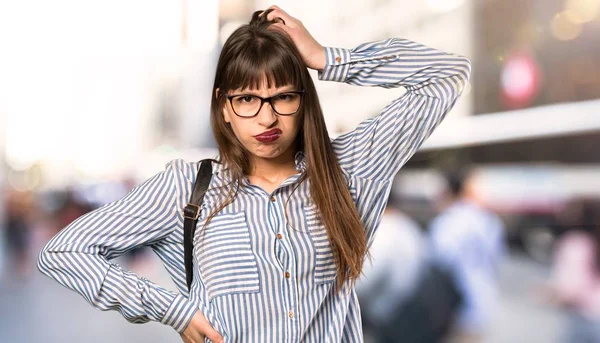 Woman with glasses with an expression of frustration and not understanding at outdoors