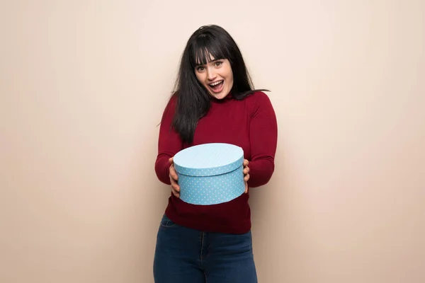 Young woman with red turtleneck surprised because has been given a gift