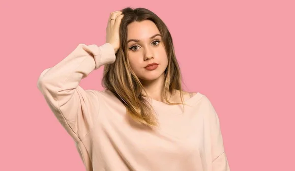 欲求不満の表現と 孤立したピンクの背景を理解していないピンクのセーターを持つティーンエイジャーの女の子 — ストック写真