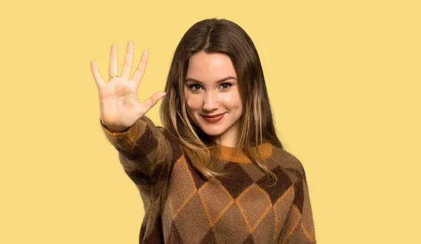 茶色のセーターを持つティーンエイジャーの女の子は 孤立した黄色の背景上の指で5を数えます — ストック写真