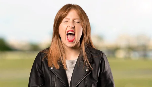 屋外で大きく開いた口で前面に叫ぶ若い赤毛の女性 — ストック写真