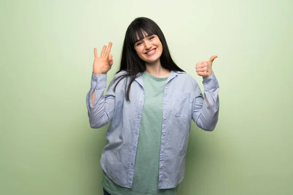 Young Woman Green Wall Showing Sign Giving Thumb Gesture — Stock Photo, Image