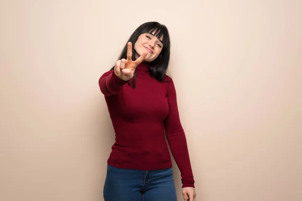 Jonge Vrouw Met Rode Coltrui Glimlachen Tonen Overwinning Teken — Stockfoto