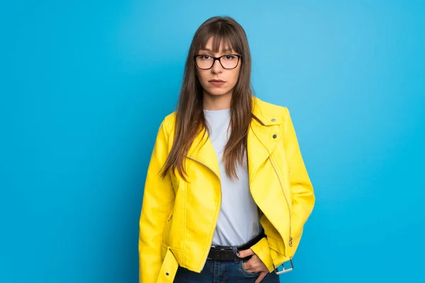 Young woman with yellow jacket on blue background portrait