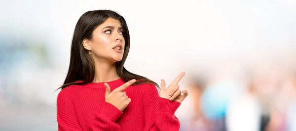 Menina Adolescente Com Suéter Vermelho Assustado Apontando Para Lado Livre — Fotografia de Stock