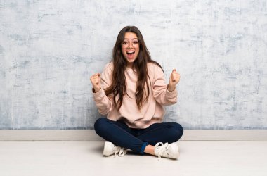 Bir masada okuyan genç öğrenci kız kazanan pozisyonda bir zafer kutluyor