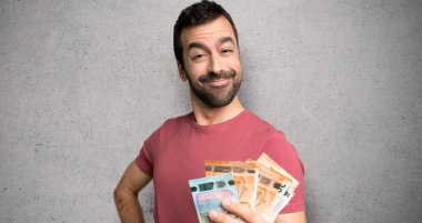 Adam kalça ve dokulu duvar üzerinde gülümseyen silah ile poz çok para alarak