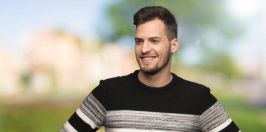 Yakışıklı adam kalça silah ile poz ve açık havada gülümsüyor