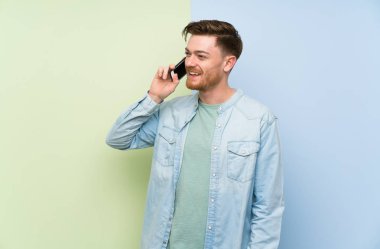 Renkli arka plan üzerinde Redhead adam cep telefonu ile bir konuşma tutmak