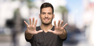 Siyah gömlek ile adam açık havada parmaklarla on sayma