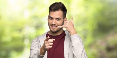 Sweatshirt ile adam telefon jest yapma ve bir parkta ön işaret