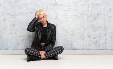 Yerde oturan genç bir kadın hayal kırıklığıyla dolu ve anlamayan bir ifadeyle