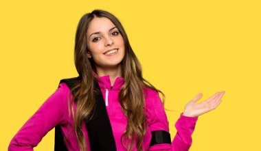 Genç izole sarı arka plan üzerinde bir reklam eklemek boşaltmak hayali avuç içinde tutan kadın spor