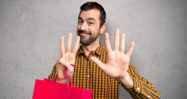 Dokuma duvar üzerinde parmaklar ile sekiz sayma alışveriş çantaları ile adam