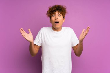 Yüzünde şok ifadesi olan, izole edilmiş mor bir duvarın üzerinde yaşayan genç bir Afrikalı Amerikalı.