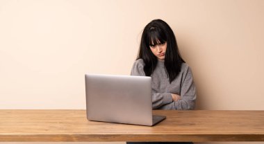 Dizüstü bilgisayarıyla çalışan genç bir kadın üzgün hissediyor.