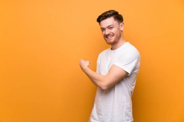 Redhead adam kahverengi duvar üzerinde geri işaret