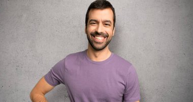 Yakışıklı adam kalça ve dokulu duvar üzerinde gülümseyen silah ile poz