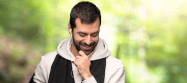 Spor adam bir parkta çene eli aşağı bakıyor