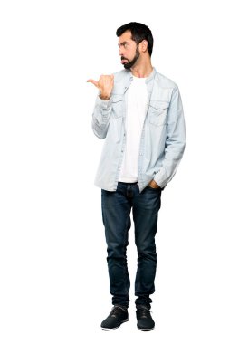 Mutsuz ve izole beyaz arka plan aşağı işaret eden sakallı yakışıklı adam tam uzunlukta atış